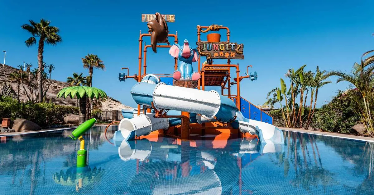 Kinderwaterpark Jungle Park van H10 Costa Adeje Palace in La Caleta, Tenerife, met gesloten glijbanen en palmen rond het bad